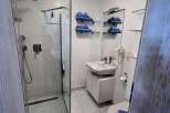 Step into this modern bathroom, featuring a sleek glass shower enclosure and pristine white tiling.