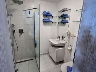 Step into this modern bathroom, featuring a sleek glass shower enclosure and pristine white tiling.
