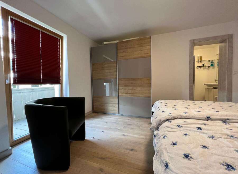 Discover the charm of this inviting bedroom, featuring a stylish black armchair and a modern wardrobe.