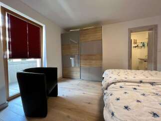Discover the charm of this inviting bedroom, featuring a stylish black armchair and a modern wardrobe.