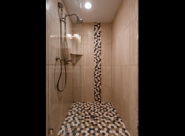 This luxurious bathroom boasts a spacious shower with elegant fixtures and a stunning mosaic tile design.