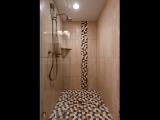 This luxurious bathroom boasts a spacious shower with elegant fixtures and a stunning mosaic tile design.