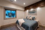 This stunning bedroom boasts a cozy and elegant design, featuring a plush bed with a soft, textured comforter and a large window offering breathtaking views of a snow-covered landscape.