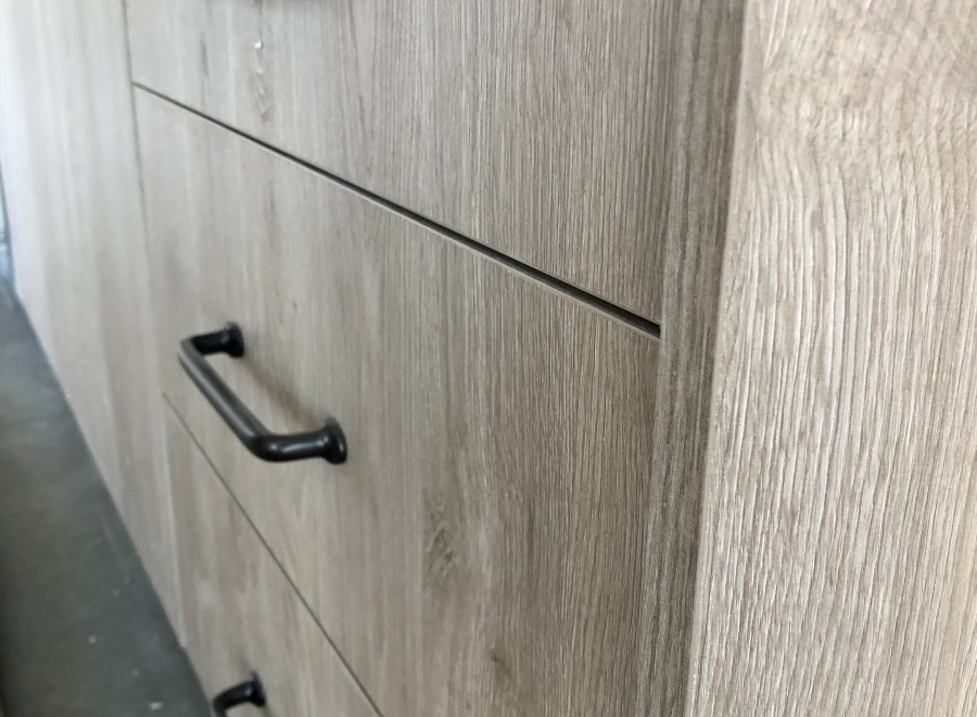 Modern kitchen cabinets with sleek black handles and a light wood grain finish.