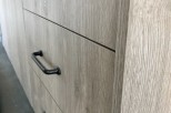 Modern kitchen cabinets with sleek black handles and a light wood grain finish.
