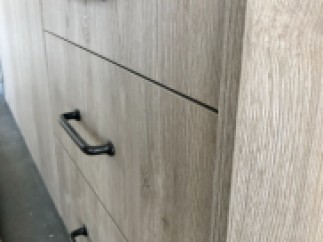 Modern kitchen cabinets with sleek black handles and a light wood grain finish.