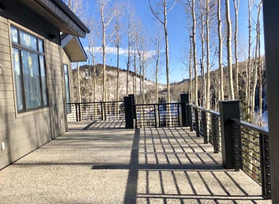 This stunning property boasts a spacious deck with modern metal railings, offering breathtaking views of the snow-capped mountains and aspen trees.