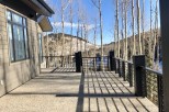 This stunning property boasts a spacious deck with modern metal railings, offering breathtaking views of the snow-capped mountains and aspen trees.