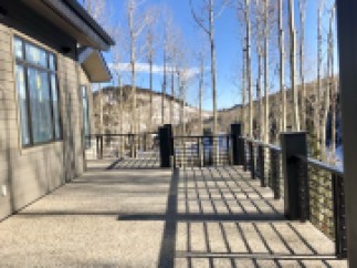 This stunning property boasts a spacious deck with modern metal railings, offering breathtaking views of the snow-capped mountains and aspen trees.