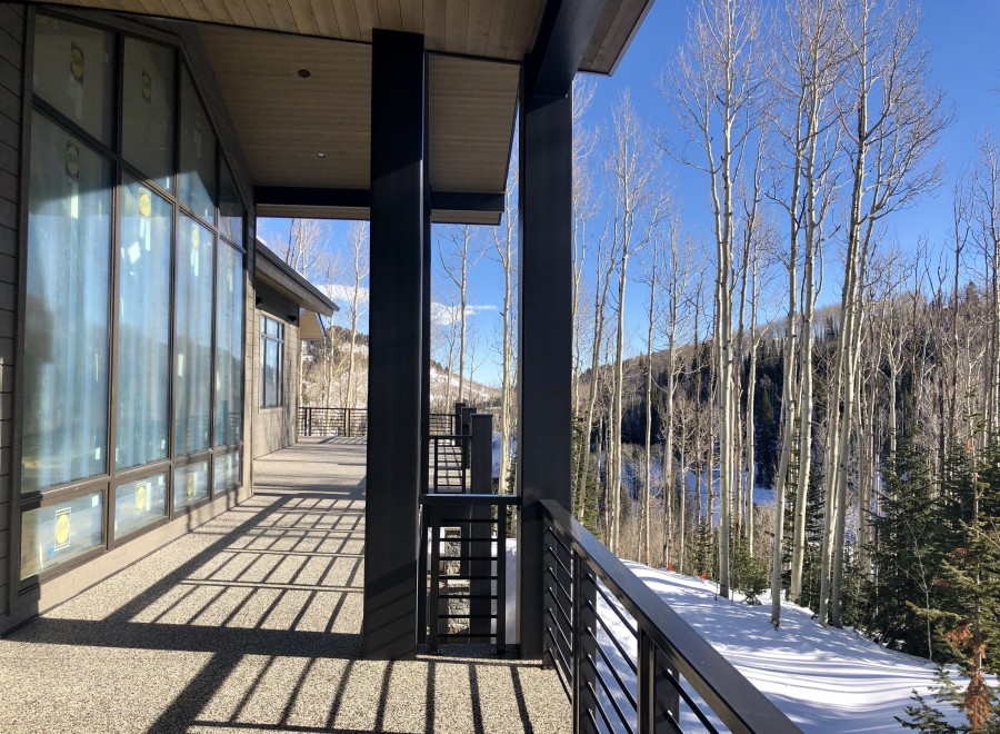 Luxury mountain home with expansive windows offering breathtaking views of snow-covered landscape and aspen trees.