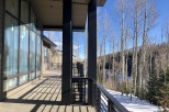 Luxury mountain home with expansive windows offering breathtaking views of snow-covered landscape and aspen trees.