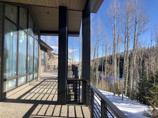 Luxury mountain home with expansive windows offering breathtaking views of snow-covered landscape and aspen trees.