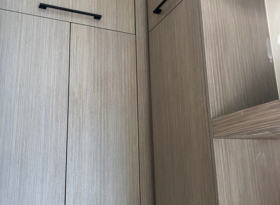 Modern kitchen cabinets with sleek, black hardware and a light gray wood grain finish.