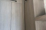 Modern kitchen cabinets with sleek, black hardware and a light gray wood grain finish.