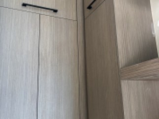 Modern kitchen cabinets with sleek, black hardware and a light gray wood grain finish.