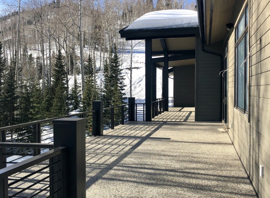 Luxury mountain home with expansive deck boasting stunning views of snow-covered landscape.