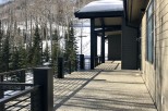 Luxury mountain home with expansive deck boasting stunning views of snow-covered landscape.