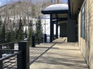 Luxury mountain home with expansive deck boasting stunning views of snow-covered landscape.