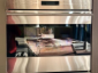 This stunning kitchen features a built-in Wolf double oven, boasting a sleek stainless steel finish and modern design.