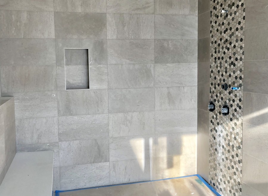 This stunning bathroom boasts a spacious shower with a built-in seat and a modern hexagonal mosaic tile accent wall.
