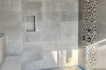 This stunning bathroom boasts a spacious shower with a built-in seat and a modern hexagonal mosaic tile accent wall.