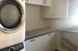 This stunning laundry room boasts modern white cabinets, sleek countertops, and high-end Electrolux washer and dryer.