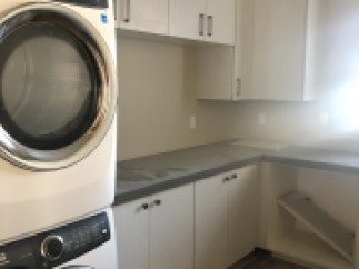 This stunning laundry room boasts modern white cabinets, sleek countertops, and high-end Electrolux washer and dryer.