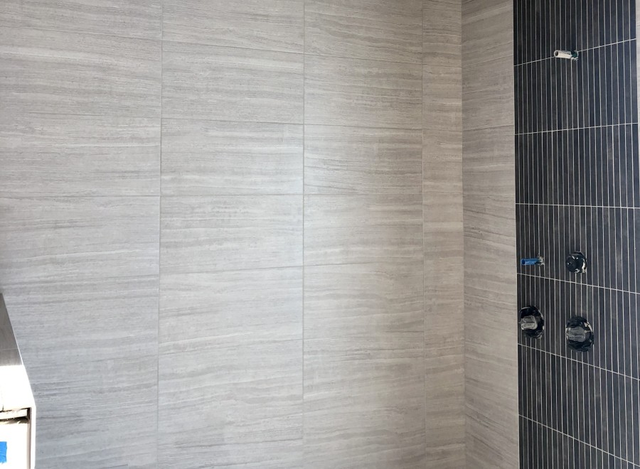 This stunning bathroom boasts a luxurious shower with a unique combination of light gray and dark gray tiles.