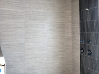 This stunning bathroom boasts a luxurious shower with a unique combination of light gray and dark gray tiles.