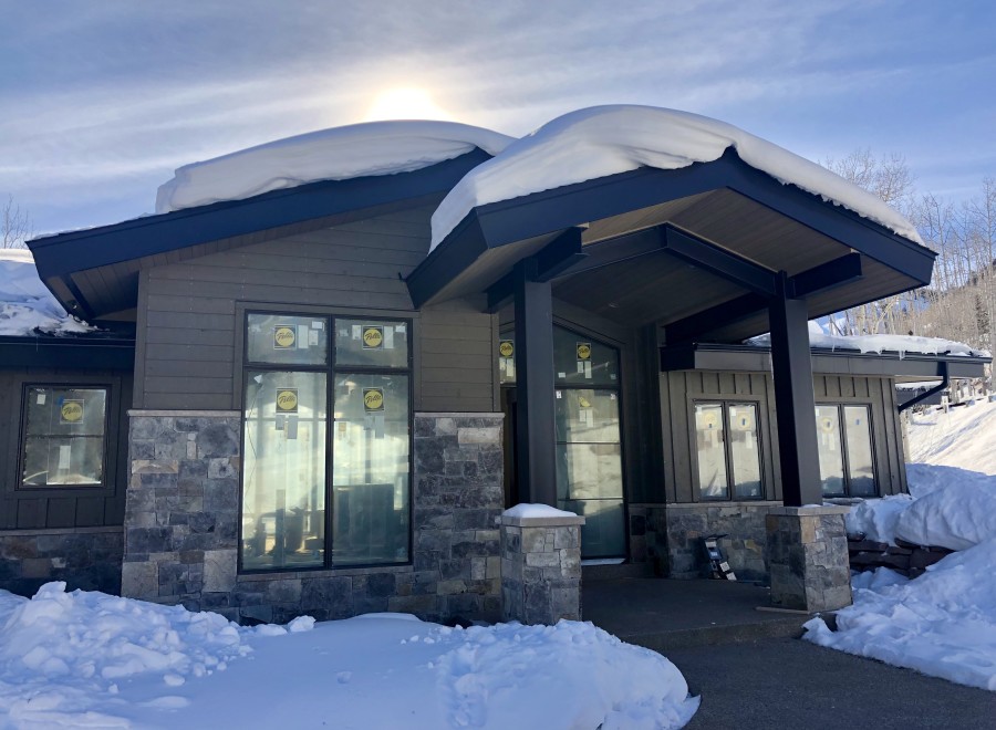 Stunning mountain home with a modern design, featuring a gray exterior, large windows, and stone accents.