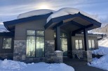 Stunning mountain home with a modern design, featuring a gray exterior, large windows, and stone accents.
