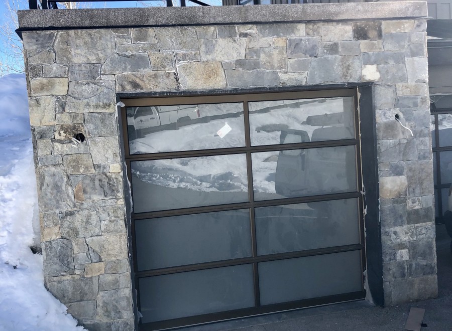 This stunning property boasts a modern stone exterior with a sleek, contemporary garage door.