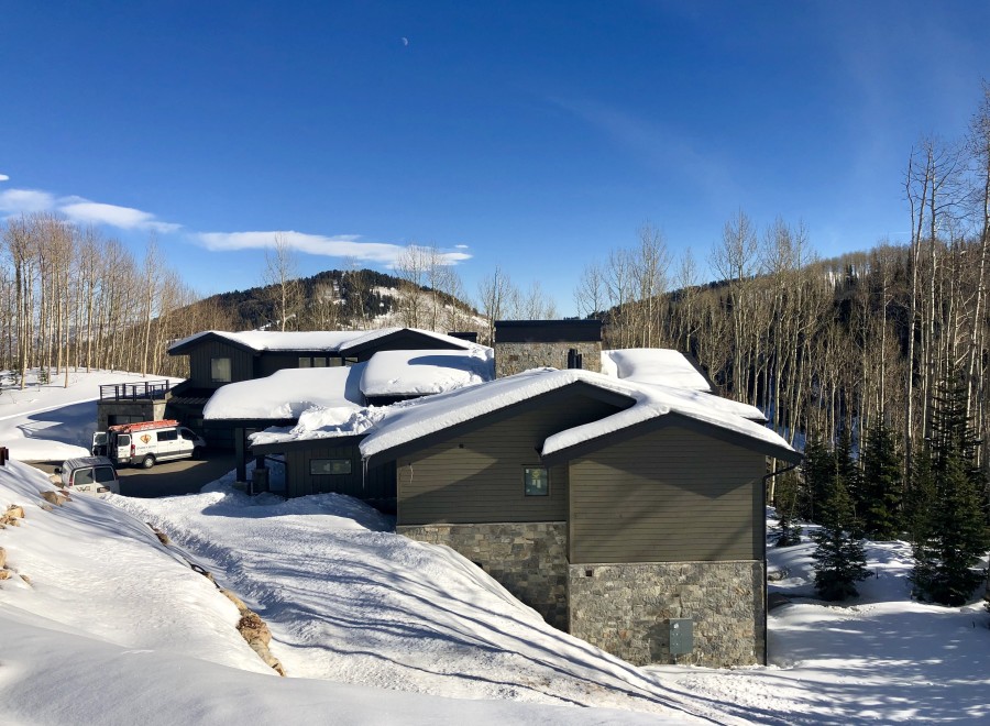 Luxury mountain home with stunning views and snow-covered roof.