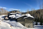 Luxury mountain home with stunning views and snow-covered roof.