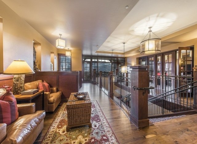 This luxurious lodge boasts a stunning hallway with hardwood floors, leather seating areas, and large windows offering breathtaking mountain views.
