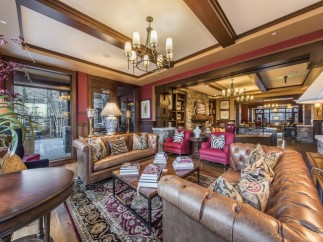Luxurious lodge with a grand lobby featuring comfortable leather sofas, a beautiful oriental rug, and a stunning stone fireplace.