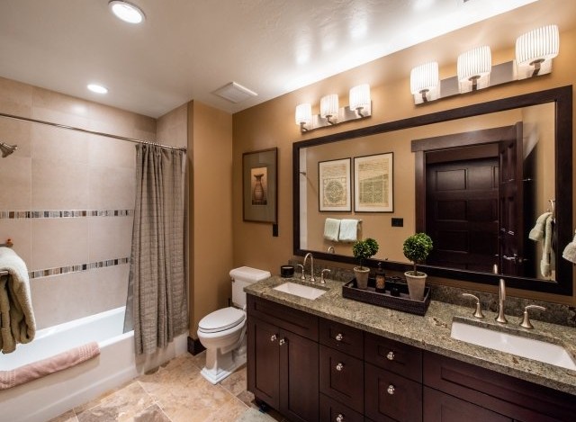 This luxurious bathroom boasts a spacious double vanity with granite countertops and dark wood cabinets.