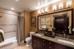 This luxurious bathroom boasts a spacious double vanity with granite countertops and dark wood cabinets.