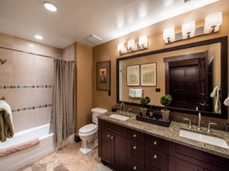 This luxurious bathroom boasts a spacious double vanity with granite countertops and dark wood cabinets.