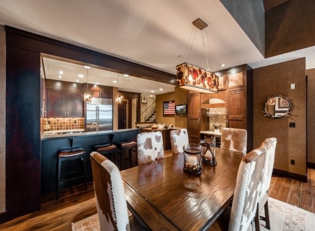This stunning property boasts a spacious dining area with a rustic-chic design, featuring a large wooden table and cowhide chairs.