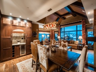 This luxurious mountain home boasts a stunning open-concept living area with floor-to-ceiling windows offering breathtaking views.