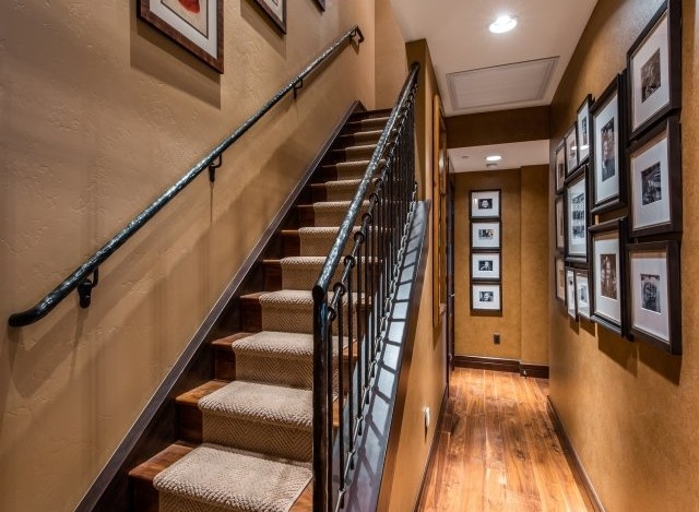 This stunning home boasts a grand staircase with wrought iron railings and plush carpeting, adding elegance to the interior.