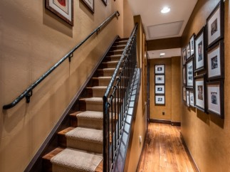 This stunning home boasts a grand staircase with wrought iron railings and plush carpeting, adding elegance to the interior.