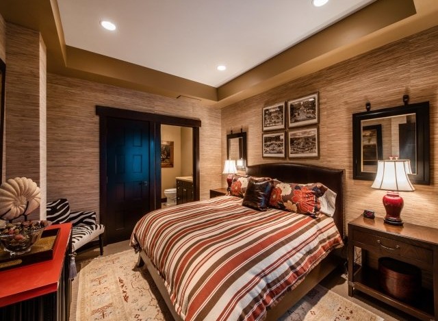 This luxurious bedroom boasts a king-size bed with a striped comforter, complemented by a plush carpet and stylish nightstands.