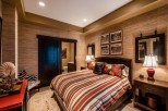 This luxurious bedroom boasts a king-size bed with a striped comforter, complemented by a plush carpet and stylish nightstands.