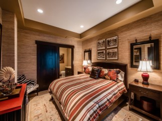 This luxurious bedroom boasts a king-size bed with a striped comforter, complemented by a plush carpet and stylish nightstands.