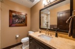This luxurious bathroom boasts a spacious vanity with a beige countertop and dark brown cabinetry, complemented by a large framed mirror reflecting the elegant shower area.