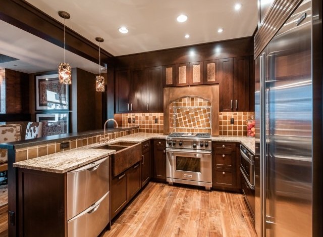 This stunning kitchen boasts a custom copper farmhouse sink, high-end stainless steel appliances, and rich dark wood cabinetry.