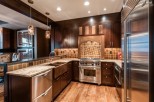 This stunning kitchen boasts a custom copper farmhouse sink, high-end stainless steel appliances, and rich dark wood cabinetry.