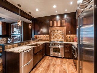 This stunning kitchen boasts a custom copper farmhouse sink, high-end stainless steel appliances, and rich dark wood cabinetry.